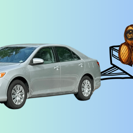 A silver Toyota Camry is positioned on the left side of the image against a gradient background that transitions from light green to blue. On the right, a black-and-white illustration of a trailer filled with wooden beer barrels is attached to the car, humorously exaggerating the concept of measuring the car’s hail damage in terms of a “keg party’s worth.”